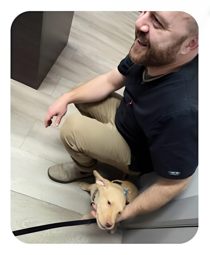 Man crouching holding small tan puppy
